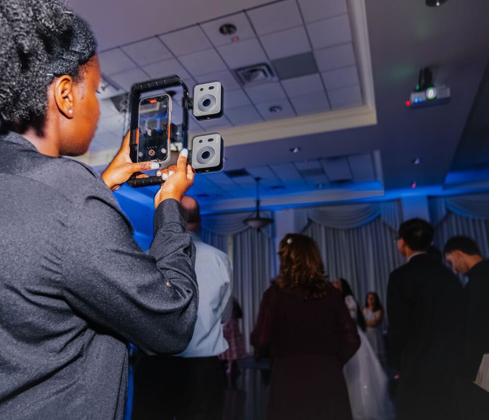 woman holding an iPhone recording a video at a wedding reception